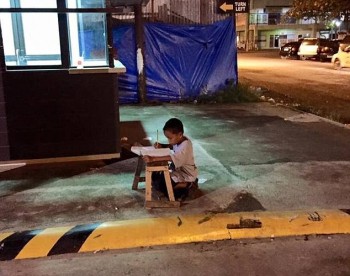 Homeless Philippino boy studying under a McDonald's light
